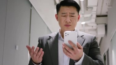 Hayal kırıklığına uğramış Asyalı orta yaşlı erkek Çinli işadamı cep telefonunda kötü bir mesaj okudu. Borç batması, iflas sorunu, ofis telefonunda şok sorunu.