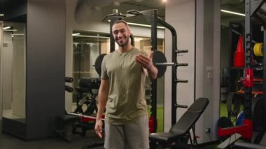 Hareket eden zoom kamera güçlü Afrikalı Amerikalı erkek fitness antrenörü spor sporcusu sporcusu olmaya davet ederek spor salonuna davet ediliyor.