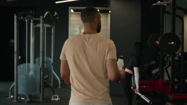 Arkaya bakan Afrikalı Amerikalı erkek sporcu atletizm antrenörü spor kulübü vücut geliştiricisi boksör spor salonundaki antrenmandan sonra spor salonuna yürür su şişesi şişesiyle gider.