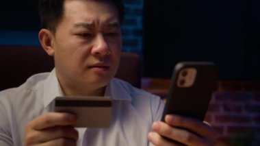 Şaşırmış Asyalı adam başarısızlığı Koreli iş adamı banka kredi kartı çevrimiçi ödeme sorunu para akışını engelledi akşam ofisinde cep telefonu hatası