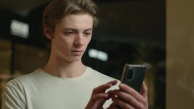 Şaşırtıcı heyecanlı beyaz erkek öğrenci erkek öğrenci müşteri çılgın duygusal mutlu tüketici cep telefonu kazanma iddiası zafer amacını kutluyor cep telefonu piyango sürprizini çevrimiçi kazandı