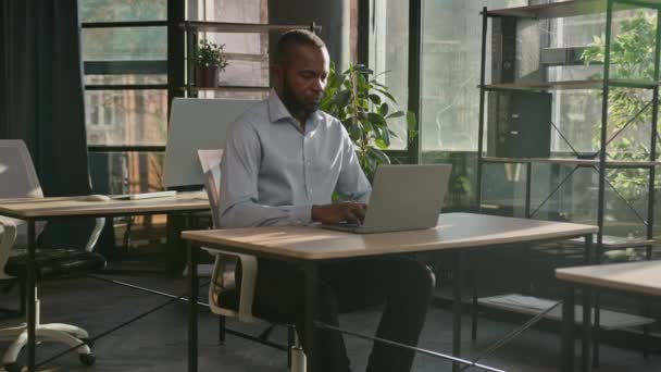 アフリカ系アメリカ人の成熟したビジネスマンの仕事のプロジェクトは 日当たりの良いオフィスでラップトップ上の電子メールを入力します — ストック動画