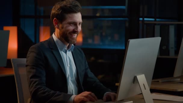 コンピュータタイプの電子メールの調査のビジネスウェブサイトのオンラインEコマースで働く白人の中年のビジネスマンの従業員マネージャーを微笑む 幸せな男性労働者の夜のオフィス仕上げ作業に満足 — ストック動画