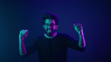 Ultraviyole neon stüdyo arka plan şampiyonu mutlu Hintli adam. Kodlama başarısı. Şampiyonluk kazanan taraftar desteği.