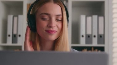 Rahatlamış gülümseyen beyaz kız girişimci. İşe ara ver. Kulaklıkla müzik dinle. Dizüstü bilgisayarla şarkının tadını çıkar.