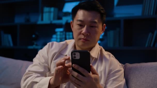 Azji Średnim Wieku Mężczyzna Nocy Domu Kanapie Przewijanie Aplikacji Telefon — Wideo stockowe