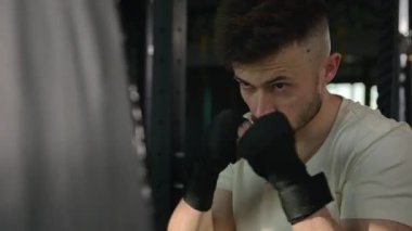Kafkasyalı boksör boksör eğitim kutusu dövüşü dövüşü spor malzemelerini kullanın. Güçlü motivasyona sahip sporcu spor salonunda profesyonel boks antrenmanı yaparak dövüş çantasına vuruyor.