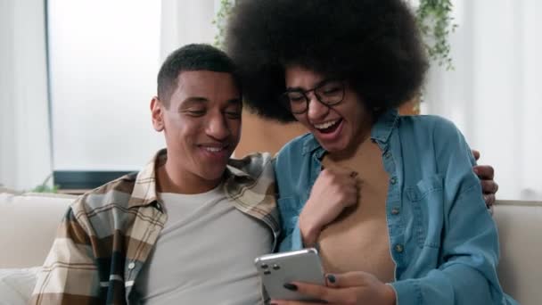 African American Ευτυχισμένο Ζευγάρι Που Διασκεδάζουν Χρησιμοποιώντας Smartphone Ενθουσιασμένοι Περιήγηση — Αρχείο Βίντεο