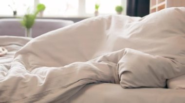 Hareketli çekim sakin sakin beyaz kadın rahat bir otel odasında rahat bir yatakta uyuyor sabah uyukluyor apartman dairesinde sağlık hizmetleri dengesi yumuşak beyaz çarşafları gevşetiyor.