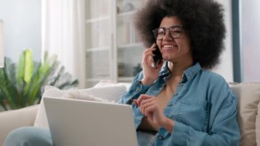 Cep telefonuyla konuşan Afro-Amerikalı bir kız. Bilgisayarla çalışıyor. İnternetten yemek siparişi veriyor.