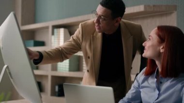 Afrika kökenli Amerikalı erkek lider akıl hocası kadın çalışana bilgisayar bilgisayarında internetteki işi açıklarken çeşitli gülümseyen iş kadınlarının ofiste çalışmasına yardımcı oluyor.