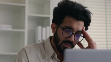 Üzgün Hintli Müslüman adam problem çözümü düşünüyor. Bilgisayarda çalışıyor. Yorgun Arap işçi işçi, borç batağından endişeleniyor.