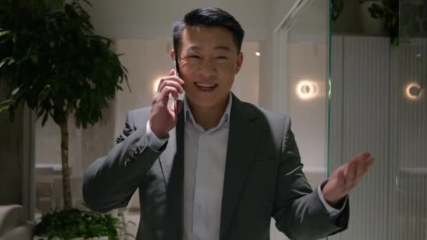 幸せな成熟した男アジアのビジネスマンオフィスロビーで笑ってビジネスミーティングに行く笑顔男性の専門家の従業員は 廊下でのんきな携帯電話の会話の議論を歩く話を交渉 — ストック動画