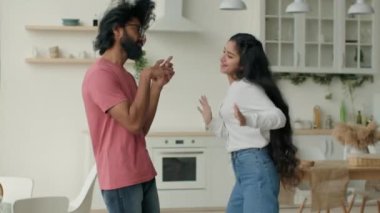 Komik çift, çok ırklı kadın ve erkek mutfakta dans ediyor enerjik çılgın dans hareketleri Arap Hint dansçıları kız ve erkek müzik dünyasına taşınıyor ev partileri yeni evde hafta sonu taşınmasını kutluyor