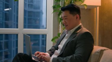 Asyalı Çinli Japon işadamı şehir merkezindeki ofis şirketinde uzaktan kumandalı bilgisayarla uzaktan kumandayı bitiriyor ve orta yaşlı tatmin olmuş bir adam projesini tamamladı.