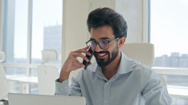 笑顔アラビアのビジネスマンマネージャー雇用主インドの男性忙しい話携帯電話オフィスでノートパソコンを作業男性起業家は 携帯電話のビジネスディスカッションを呼び出します企業のクライアントリモートチャットをコンサルティング — ストック動画