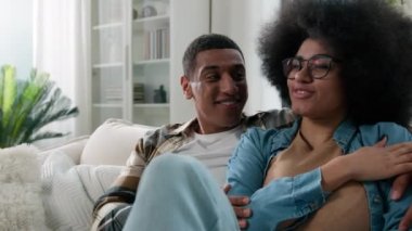 Afro-Amerikan mutlu aile çifti sevgi dolu muhabbetler sohbet sohbet konuşma gülümseme paylaşım haberleri erkek ve kız arkadaş kadın ev kanepede