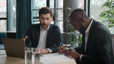Beyaz adam bankacı ajan Afrikalı Amerikalı erkek müşteri laptopuna danışır sunum yöneticisi yatırımcı sigorta sözleşmesi imzalar iki çok ırklı işadamı ofis toplantısı