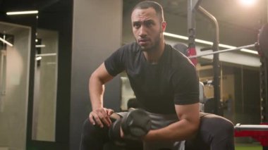 Vücut geliştirici Afrikalı Amerikalı adam spor salonunda dambılı kaldırıyor sağlıklı yaşam tarzı fitness, spor kulübü güç antrenmanı güçlü egzersiz güçlü kürek çeken güçlü kolları olan güçlü bir sporcu.