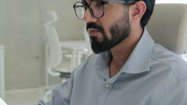 Çok düşünceli bir portre. Odaklanmış Arap Hintli Müslüman iş adamı. İş yerindeki bilgisayar problemi ile uğraşıyor.