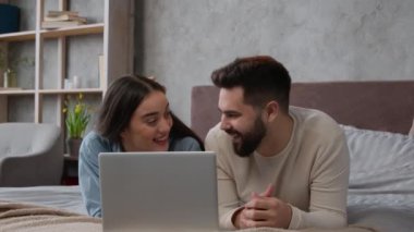 Kafkas aile çifti yatak odasında rahatlarken dizüstü bilgisayarda film izleyip gülüşmeler, video konuşmaları gülüşmeler, gülüşmeler, gülücükler, kadın adam yatak alışverişi siparişlerinde birlikte dinleniyor.