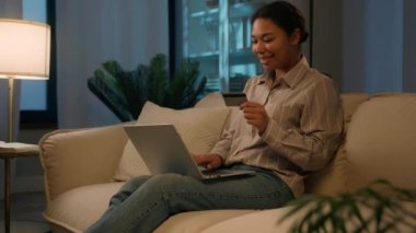 Afro-Amerikalı kadın müşteri kredi kartı online alışveriş sitesi ödemesini dizüstü bilgisayarda kullanıyor. Ev müşterisi mutlu müşteri web sitesinden yemek siparişi veriyor. Yemek teslimatı için e-bankacılık parası satın alıyor.