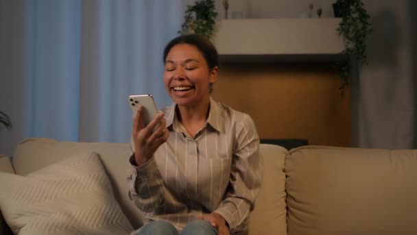 Glimlachend Meisje Afro Amerikaanse Vrouw Avonds Thuis Bank Kijken Mobiele — Stockvideo