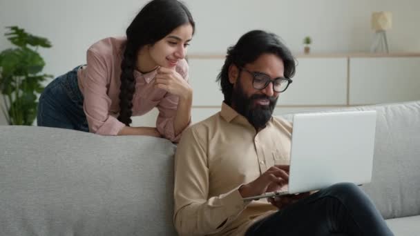 在总部工作的阿拉伯商人自由职业者印度女人的妻子站在丈夫身后多种族夫妇家庭在笔记本电脑网站上购买网上订单搜索公寓 — 图库视频影像