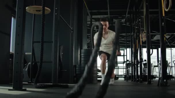 アクティブ筋肉アスリート白人スポーツマン男フィットネスジムでトレーニング重い戦闘ロープでスクワット激しい運動スポーツボディービルは良い物理的な形状健康的なライフスタイルを達成します — ストック動画