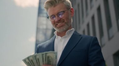 Mutlu, olgun, yaşlı girişimci zengin iş adamı orta yaşlı, zengin işadamı elinde nakit para banknotları, finansal başarı, maaş kazanç ödülü açık havada finans yatırımları.
