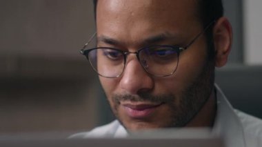 Hintli mutlu iş adamı gülümseyen Arap adam bilgisayardaki yansıma ışığına bakarak internet işi web sitesinde çalışan Amerikalı ofis işvereni kapatıyor.