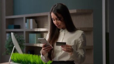 Kafkas iş kadını ayakta duran ofis çalışanı iş kadını yönetici banka müdürü telefon ve kredi kartı bankacılığı online hizmet alışverişi akıllı telefon döviz alım-satımı