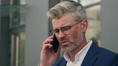 Ciddi yetişkin girişimci iş yeri yakınlarındaki şehirde orta yaşlı bir işadamı. Kafası karışmış. Cevap ver.