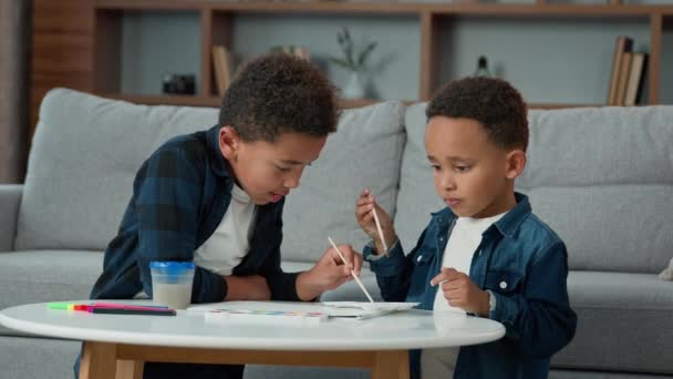 2人のアフリカ系アメリカ人の子供学校の男の子民族の小さな友人兄弟が自宅で一緒に絵を描いています — ストック動画