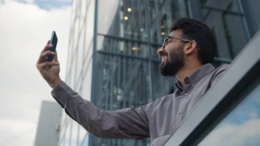 Arap işadamı Hintli girişimci cep telefonuyla konuşuyor mutlu adam konuşuyor ofis balkonunda uzak online konferans toplantısı açık havada iş konuşmaları gülüşmeler