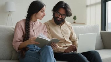 Çok ırklı bir çift olan Arap yetişkin erkek ve kadın gazete okuyorlar. Faturaları ödüyorlar. Ev kredisi ödemeleri planlıyorlar.