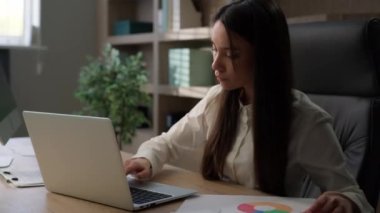 Kafkas kadın işletme müdürü ofis çalışanı masa başı iş kadını dizüstü bilgisayarla ve belgelerle çalışıyor grafik çizelgelerini kontrol ediyor bilgisayar projesi ile ilgili evrak işlerini yürütüyor veri analizi yapıyor