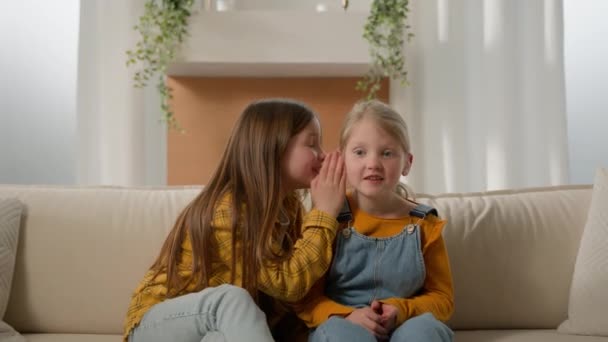 可爱的孩子们在沙发客厅里的女孩姐姐向小朋友小道消息和小朋友们分享秘密的流言蜚语和好友们一起玩家庭关系友谊 — 图库视频影像
