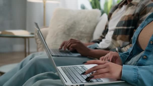 認識できないカップルの男アフリカの女性のボーイフレンドのガールフレンドの男の女の子のユーザーハッカーゲーマーは ソファソファのソファの家でラップトップでオンラインで作業している2台のコンピュータを使用してゲーム中毒フリーのブラウジングPc — ストック動画