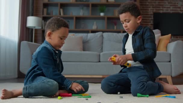 两名非洲裔美国儿童男孩族裔朋友兄弟姐妹兄弟在客厅的地板上玩塑料玩具游戏玩乐儿时快乐的家庭育儿 — 图库视频影像