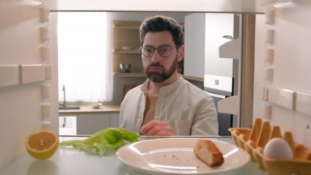 空腹の男は半分のレモンと空の冷蔵庫を開きます レタスの葉 1個の卵 パンのスライスは 溶液を見つける食品を注文します — ストック動画