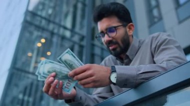 Üzgün Arap adam nakit sahibi işadamı şehir merkezinin terasında 100 dolar tutuyor. Parası yok. Asgari ücret düşük.