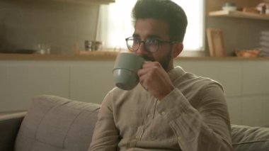 Rahat rüya gören Arap erkek memnun adam kanepede dinleniyor evde çay içiyor sabah kahvesini içiyor içkinin tadını çıkarıyor aromalı içkinin tadını çıkarıyor iyi dinlenme haftasonu yalnız başına düşün.
