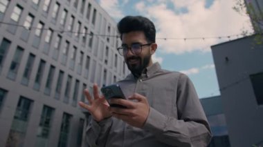 Kafası karışmış Hintli işadamı turist yer tespiti haritası uygulamasını cep telefonundaki Arap iş adamının açık havada kaybolan akıllı telefon navigasyonunu kontrol etmek için kullanıyor.