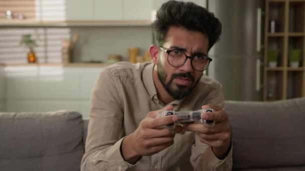 アラビア語インドの男性男性ゲーム中毒は 家庭用キッチンでソファソファの上のコントローラーで仮想スポーツをプレイテレビでオンラインコンソールゲームをプレイゲーマーはゲーム以上を失うことについて失望 — ストック動画
