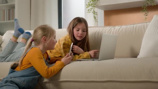 两个可爱的高加索女孩姐妹在沙发上的客厅里一起玩网络游戏 教小女孩概念 孩子和现代技术 — 图库视频影像