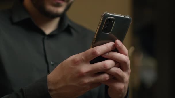 未知の男は スマートフォンのガジェットのモバイルアプリを使用して電話のテキストメッセージを入力して男性実業家タッチアップの手を閉じて携帯電話を保持します — ストック動画