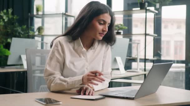 ビジネス女性アラビア語インドの女の子のビジネス女性マネージャーの労働者デスクでラップトップコンピュータを使用して女性のタイピングノートブックノートブックのアイデアを書くオフィスでオンラインPc技術で作業情報を書き込み — ストック動画