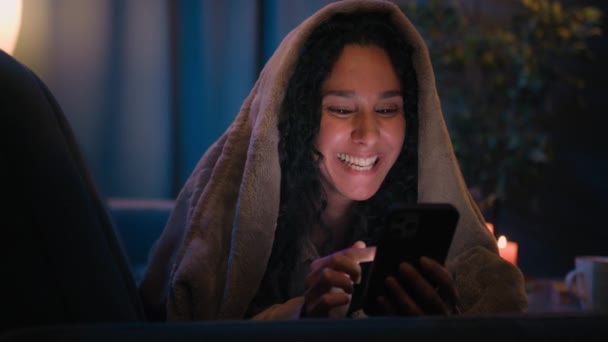 Hispanische Frau Mädchen Mit Smartphone Unter Decke Auf Bettcouch Lesen — Stockvideo