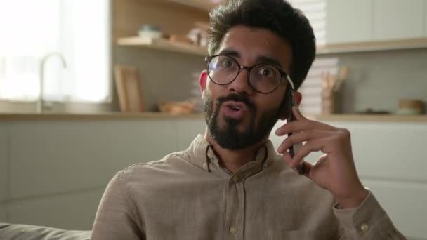 陽気なインドのアラビア人男性はキッチンで友人と携帯電話を話す幸せなイスラム教徒の男笑顔男性の家の所有者話すスマートフォン作るオンライン注文食品配達自宅で気楽なカジュアル会話 — ストック動画